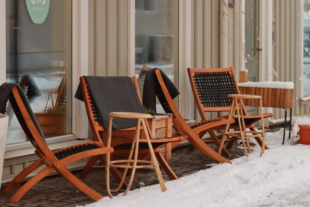 Charming outdoor cafe with wooden chairs on a snowy sidewalk, perfect for a winter scene.